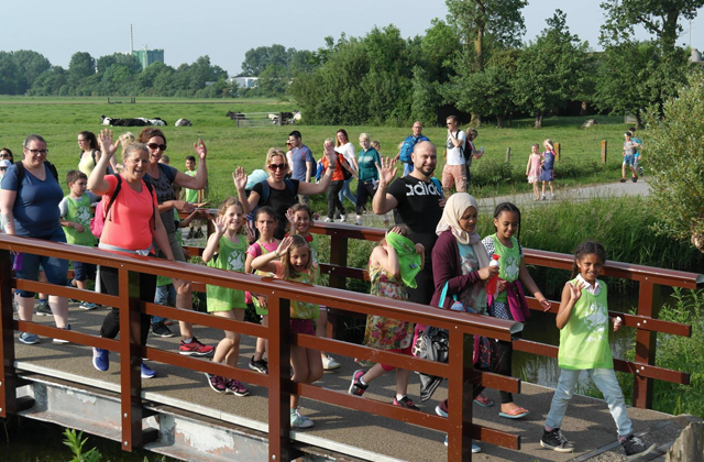 Kinderen en ouders lopen over een bruggetje tijdens de Avond4daagse Schagen