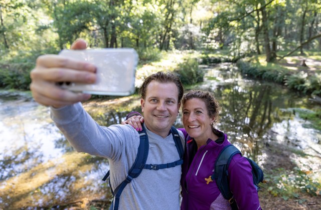 Man en vrouw maken selfie bij een vennetje in het bos