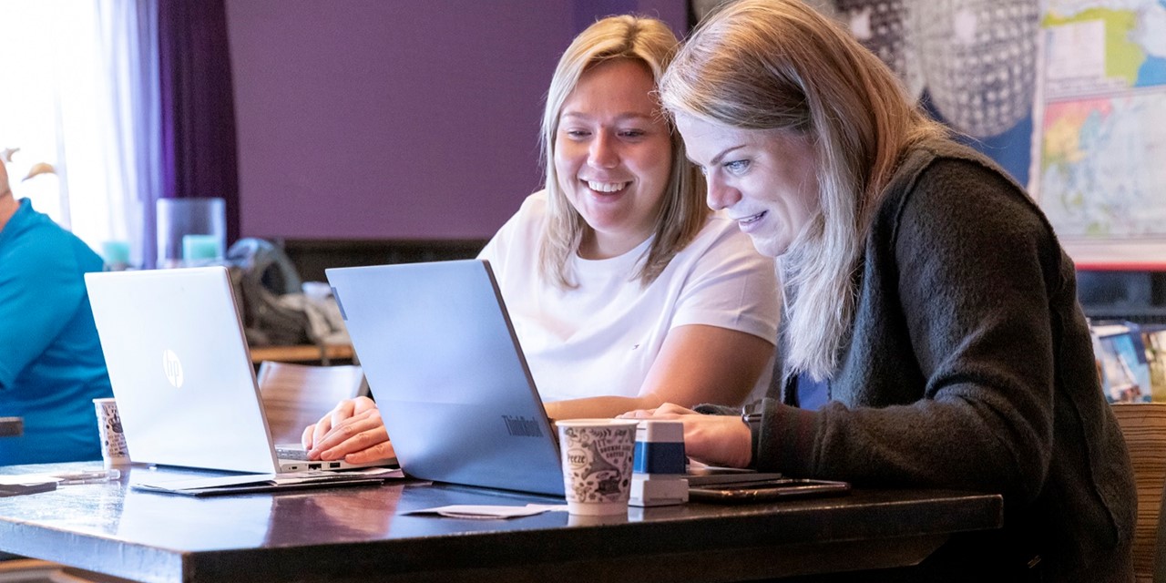 Twee vrijwilligers Exodus Wandeltocht achter de laptop