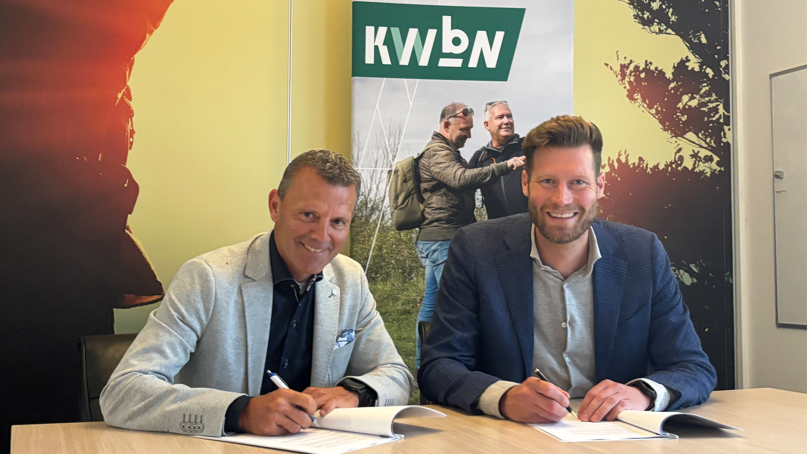 Danny van Eeckhout, Managing Director Bauerfeind Benelux en Gijs Janssen, directeur-bestuurder KWbN, kijken in de camera en ondertekenen contract