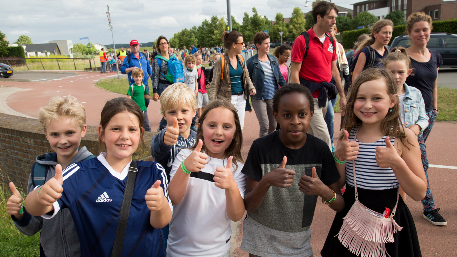 Deelnemende kinderen aan de Avond4daagse met hun duim omhoog kijken in de camera