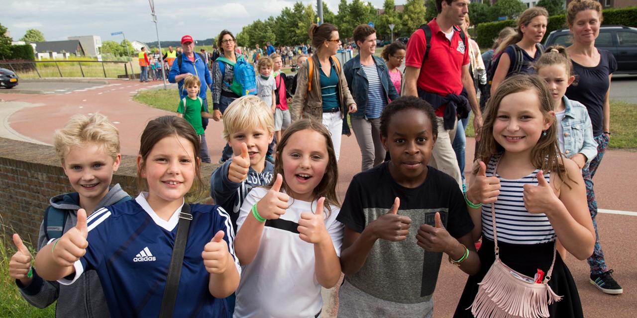 Deelnemende kinderen aan de Avond4daagse met hun duim omhoog kijken in de camera