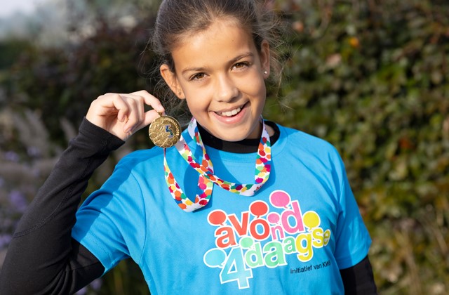 Meisje houdt Avond4daagse medaille omhoog en lacht