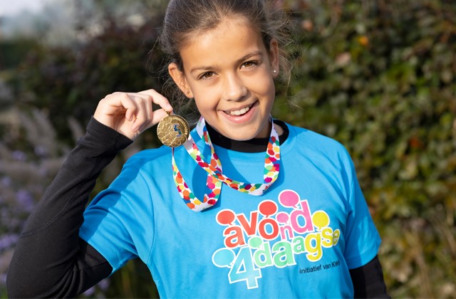 Meisje houdt Avond4daagse medaille omhoog en lacht