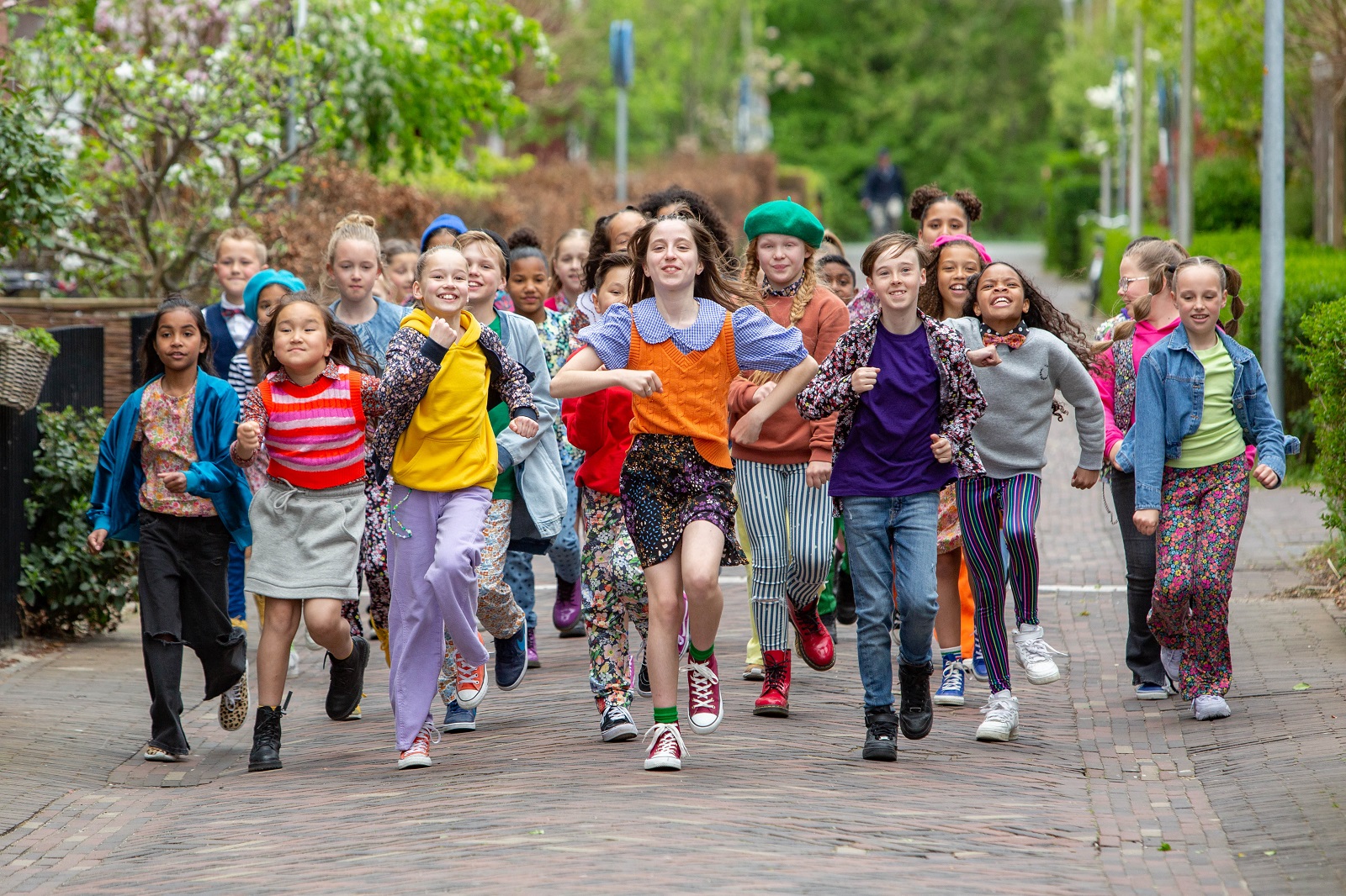 Kinderen voor Kinderen zingend en dansend over straat met lied Avond4daagse