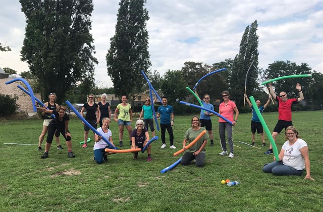 Groep mannen en vrouwen op grasveld met sportartikelen