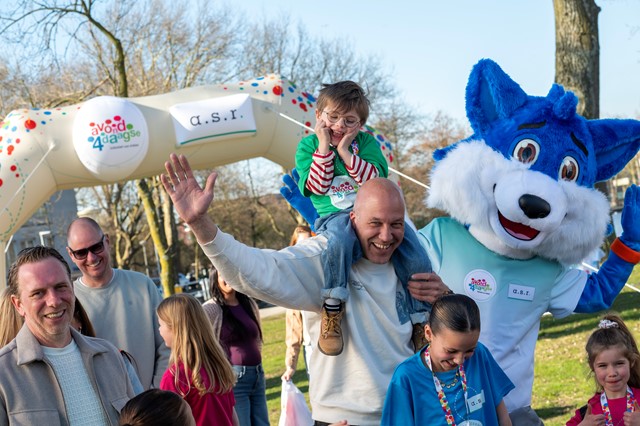 Blij kinderen en ouders met op de achtergrond de Avond4daagse startboog en mascotte Fiero