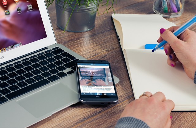 Laptop, mobiel en hand die op een kladblok schrijft