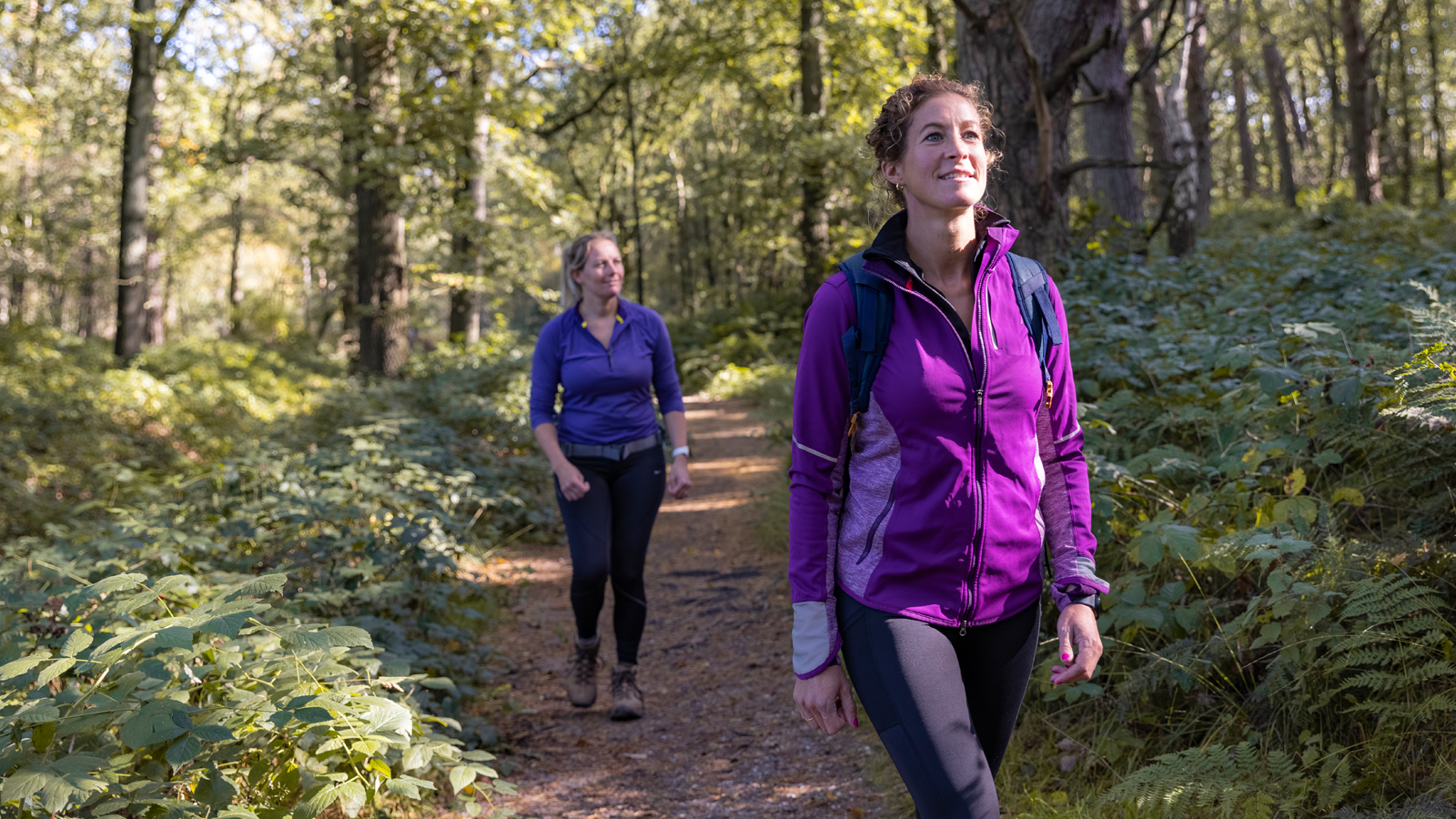 Twee dames in sportieve kleding wandelen door het bos