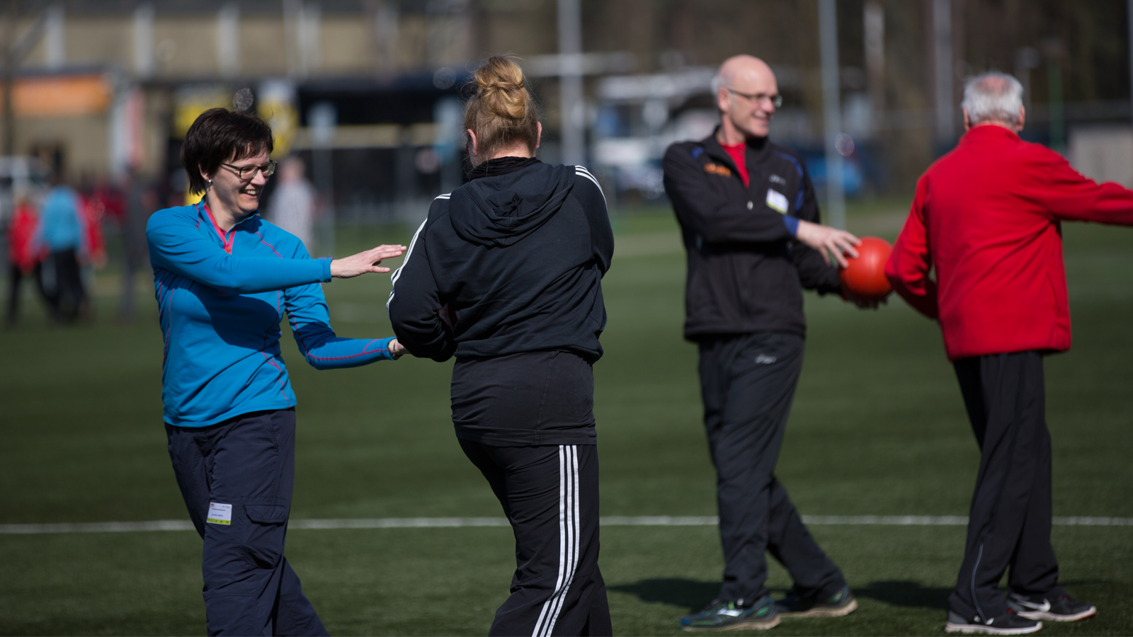 Sportief geklede mannen en vrouwen doen een oefening met een bal