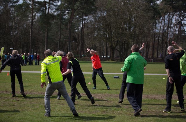 Een groep mensen doet rekoefeningen op een grasveld