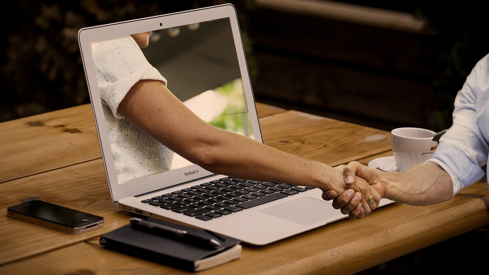 Hand steekt uit laptop en schudt andere hand