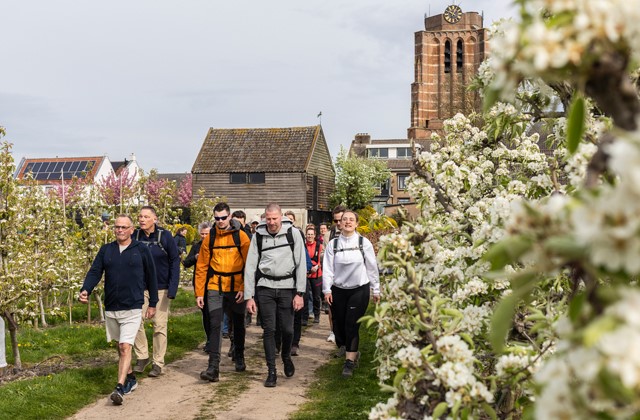 Wandelaars tussen bloesem me op de achtergrond een dorp