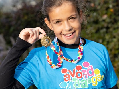 Meisje houdt Avond4daagse medaille omhoog en lacht