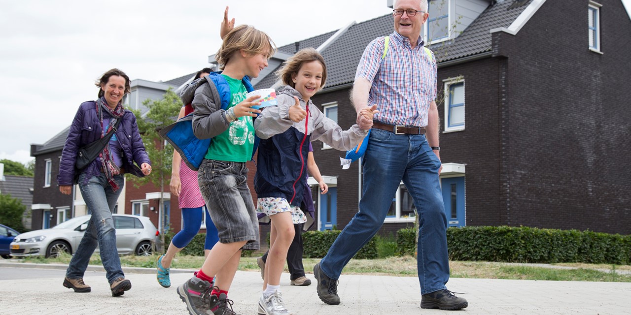 Kind steekt duim omhoog, wandelend met ouders tijdens Avond4daagse