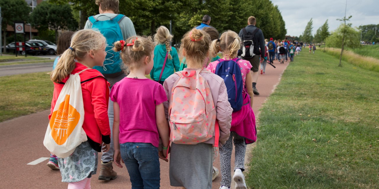 Kinderen en ouders op de rug gefotografeerd tijdens de Avond4daagse