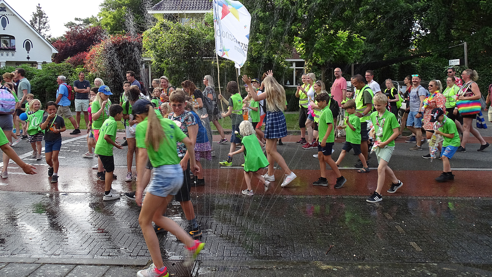 Kinderen krijgen verkoeling door een sproeier tijdens de Avond4daagse