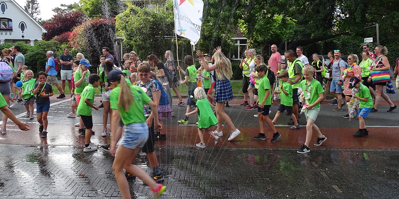 Kinderen krijgen verkoeling door een sproeier tijdens de Avond4daagse